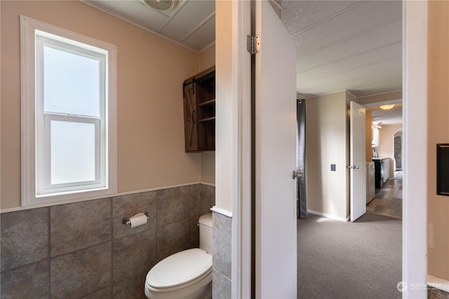 bathroom with tile walls and toilet