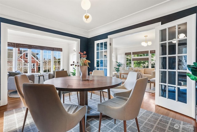 dining area with hardwood / wood-style floors, ornamental molding, and a chandelier