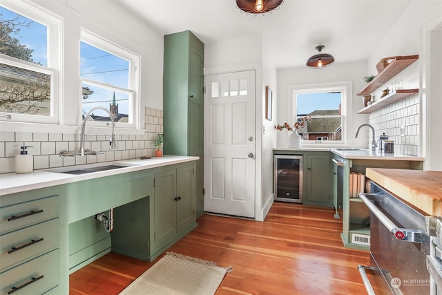 kitchen with wine cooler, green cabinetry, sink, and light hardwood / wood-style flooring