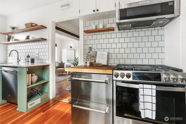 kitchen featuring stainless steel appliances, wood-type flooring, sink, and decorative backsplash