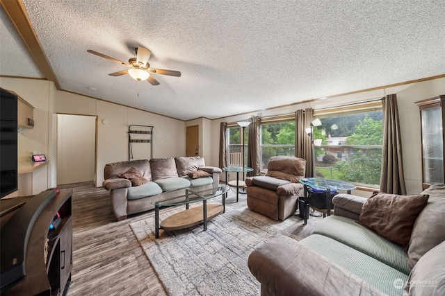 living room featuring lofted ceiling, crown molding, ceiling fan, wood-type flooring, and a textured ceiling