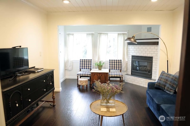 living room featuring crown molding, a brick fireplace, and dark wood-type flooring