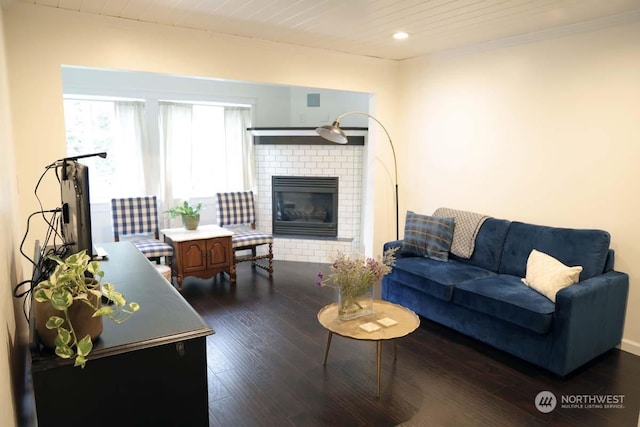 living room featuring crown molding, dark hardwood / wood-style floors, wooden ceiling, and a fireplace