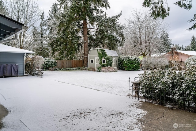 snowy yard featuring a storage shed