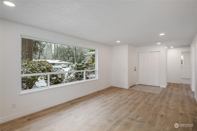 empty room with a textured ceiling and light wood-type flooring