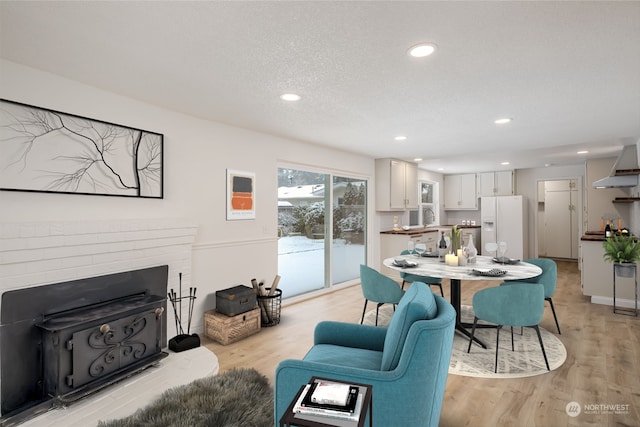 living room with a fireplace, sink, a textured ceiling, and light wood-type flooring