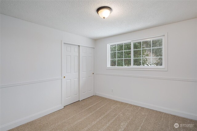 unfurnished bedroom featuring a closet, light carpet, and a textured ceiling