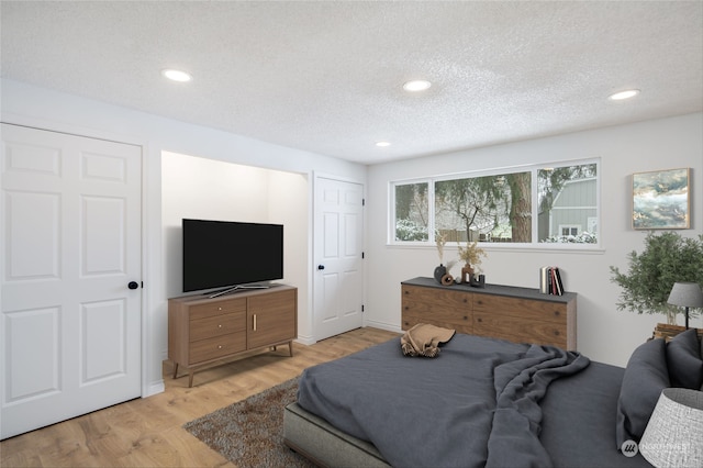 bedroom with a textured ceiling and light hardwood / wood-style floors