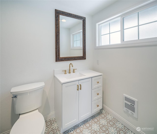 bathroom featuring vanity, toilet, and heating unit