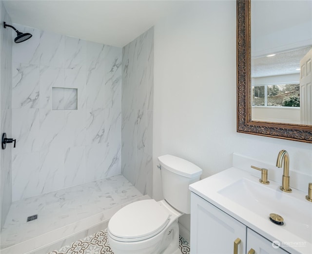 bathroom with vanity, toilet, and a tile shower