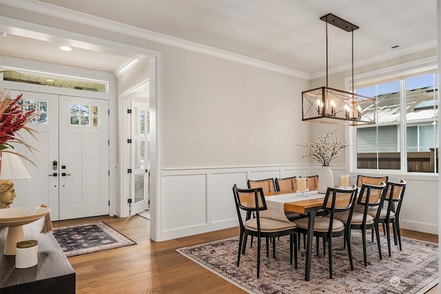 dining space with crown molding, wood-type flooring, and an inviting chandelier