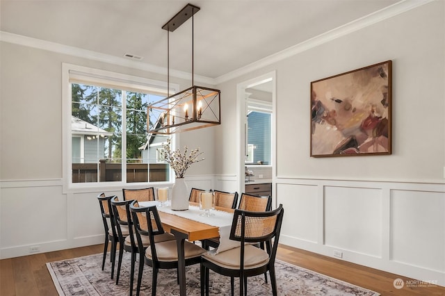 dining area featuring crown molding, wood-type flooring, and a chandelier