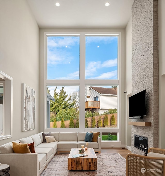 living room featuring light hardwood / wood-style flooring, a fireplace, and a high ceiling