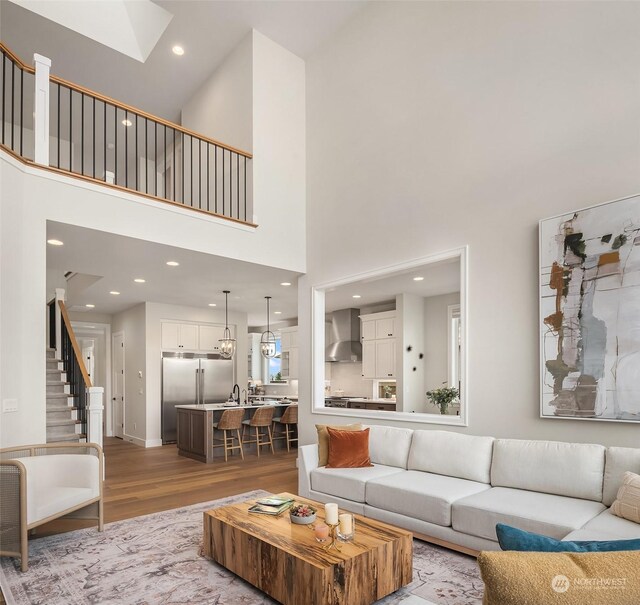 living room featuring sink, a high ceiling, and light wood-type flooring