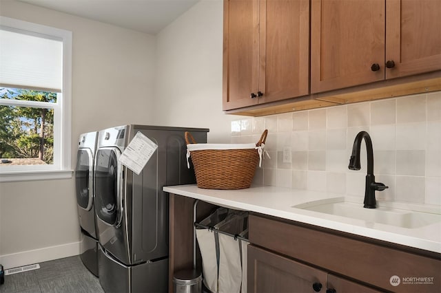 clothes washing area featuring cabinets, washing machine and clothes dryer, and sink