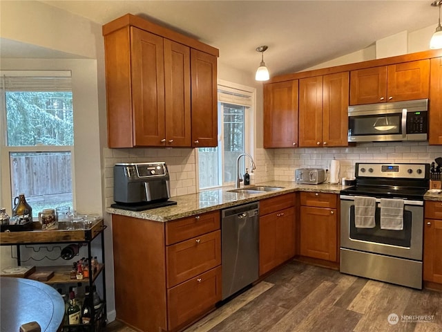 kitchen with hanging light fixtures, light stone countertops, dark hardwood / wood-style floors, and appliances with stainless steel finishes