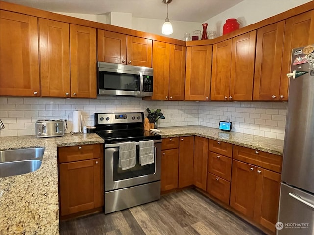 kitchen with sink, appliances with stainless steel finishes, dark hardwood / wood-style floors, light stone countertops, and decorative backsplash