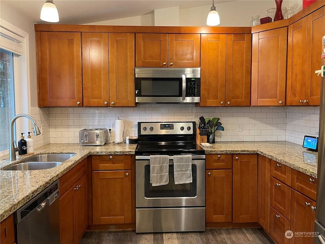 kitchen with pendant lighting, sink, backsplash, light stone counters, and stainless steel appliances