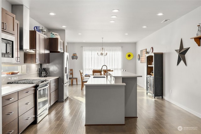 kitchen with sink, decorative light fixtures, dark hardwood / wood-style floors, an island with sink, and stainless steel appliances