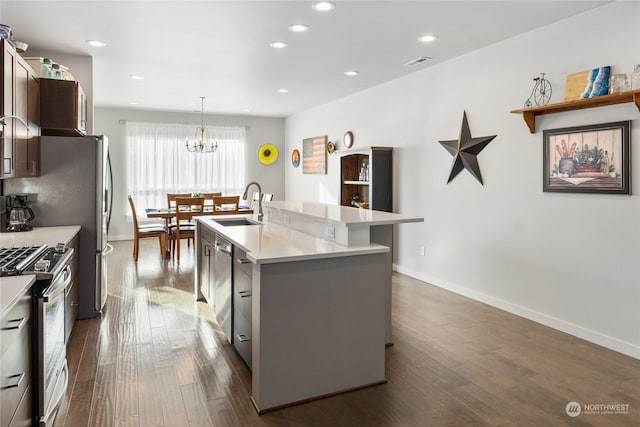 kitchen featuring sink, dark wood-type flooring, stainless steel appliances, a center island with sink, and decorative light fixtures