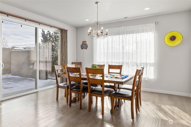 dining space with plenty of natural light, hardwood / wood-style floors, and a chandelier