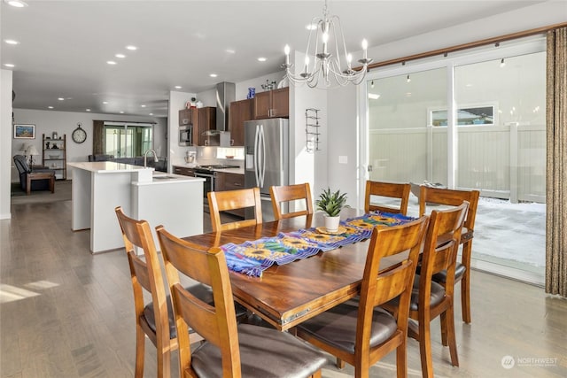 dining room featuring wood-type flooring, sink, and a chandelier