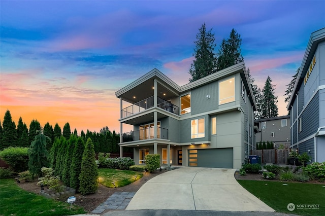 contemporary house with a balcony, a garage, and a lawn