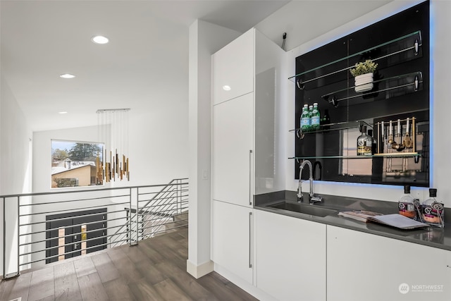 bar with dark hardwood / wood-style flooring, sink, and white cabinets