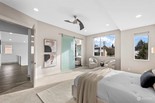 bedroom with ceiling fan, a barn door, and carpet floors