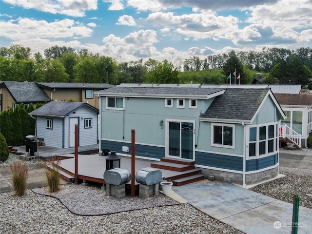 back of house featuring entry steps, a patio area, roof with shingles, and a deck