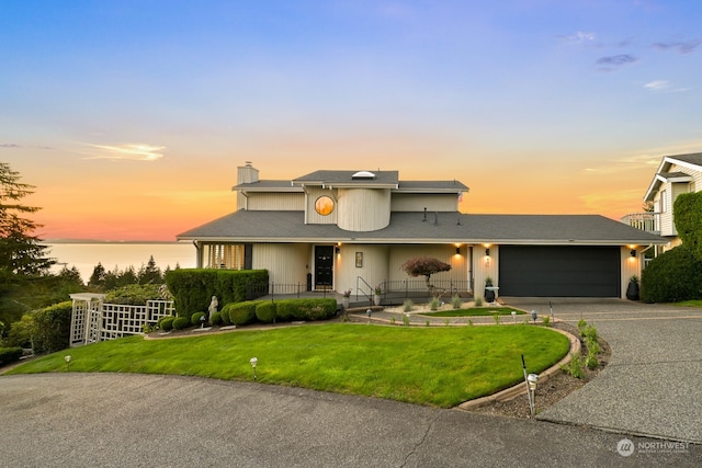 view of property with a garage, a yard, and a water view