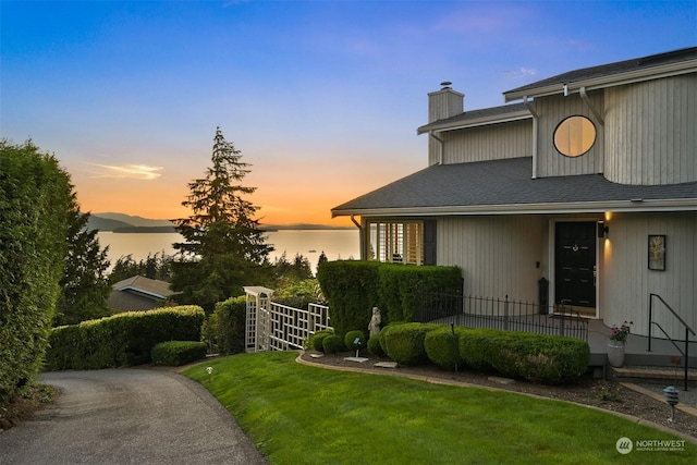 view of front of home with a yard and a water view