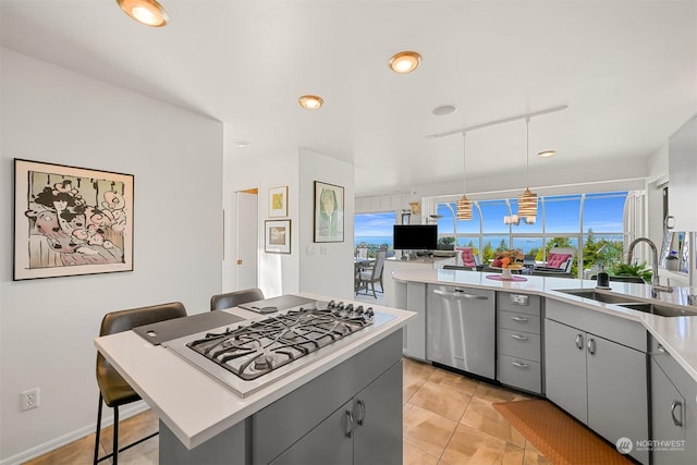 kitchen with gray cabinetry, a kitchen breakfast bar, stainless steel appliances, pendant lighting, and a center island