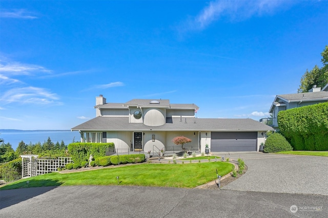 view of front facade with a water view, a front lawn, and a garage