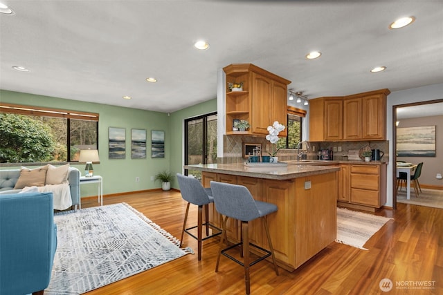 kitchen with sink, light hardwood / wood-style floors, a breakfast bar, and decorative backsplash