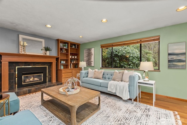 living room with a tiled fireplace and light hardwood / wood-style floors