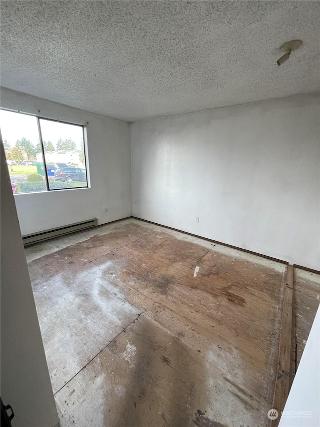 spare room featuring a baseboard heating unit and a textured ceiling