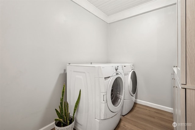 laundry area featuring crown molding, independent washer and dryer, wood-type flooring, and cabinets