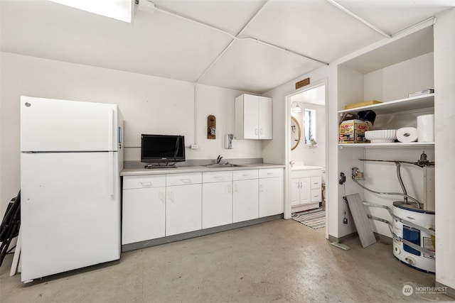 kitchen with sink, water heater, white cabinets, and white fridge