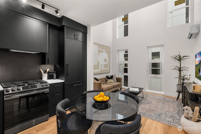 dining area featuring a high ceiling, rail lighting, and light hardwood / wood-style flooring