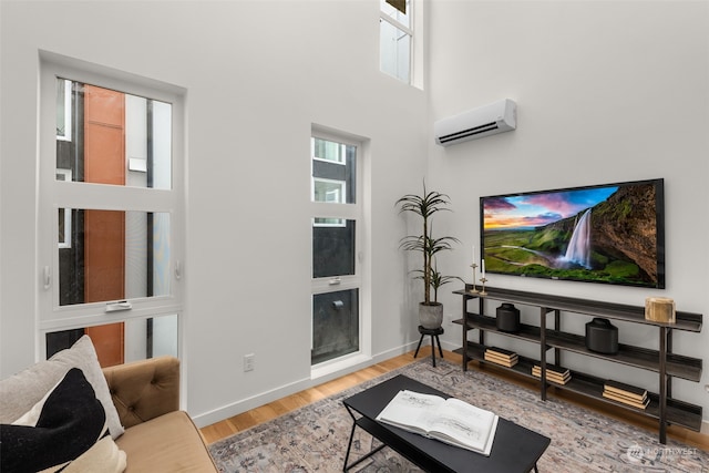 living room featuring a wall mounted air conditioner, a high ceiling, and light wood-type flooring