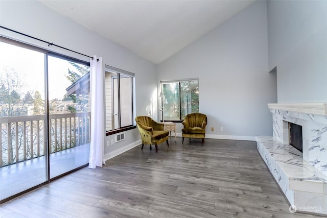 sitting room featuring high vaulted ceiling, a premium fireplace, baseboards, and wood finished floors