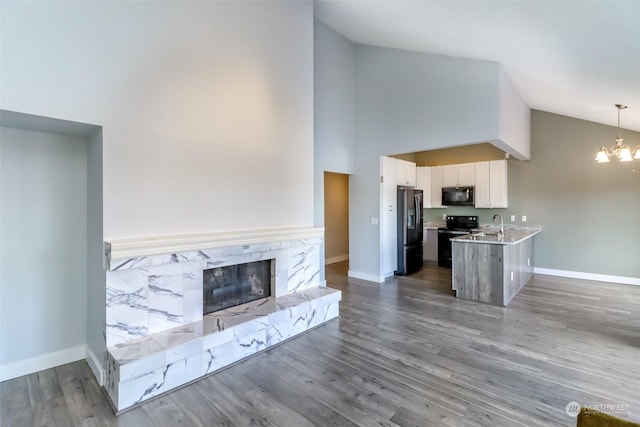 kitchen with pendant lighting, white cabinets, kitchen peninsula, stainless steel refrigerator with ice dispenser, and black / electric stove