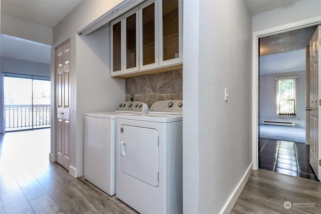 washroom with cabinets, wood-type flooring, a textured ceiling, and washing machine and clothes dryer