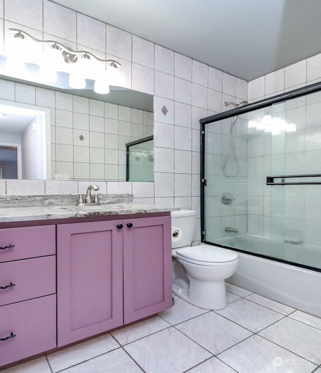 bathroom with enclosed tub / shower combo, tile patterned flooring, toilet, vanity, and tile walls