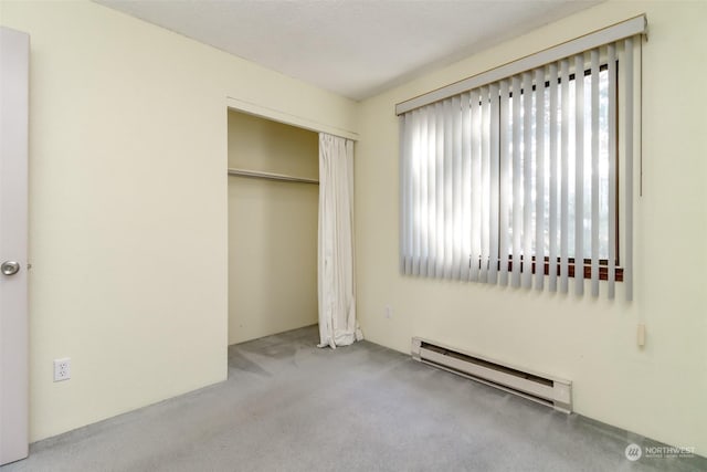 unfurnished bedroom featuring light carpet, a closet, and baseboard heating