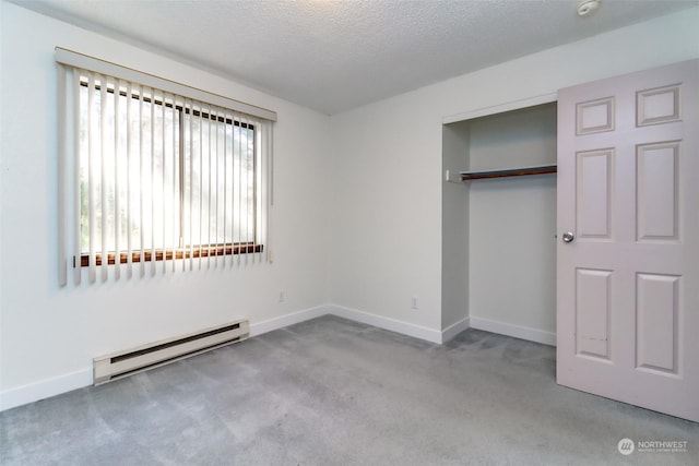 unfurnished bedroom with a baseboard heating unit, light colored carpet, a textured ceiling, and a closet