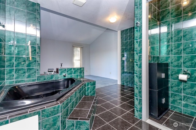 bathroom with tile patterned floors, independent shower and bath, vaulted ceiling, and tile walls