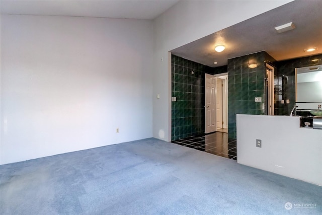 carpeted spare room featuring tile walls