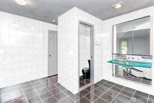 bathroom with tile patterned flooring, a textured ceiling, and tile walls